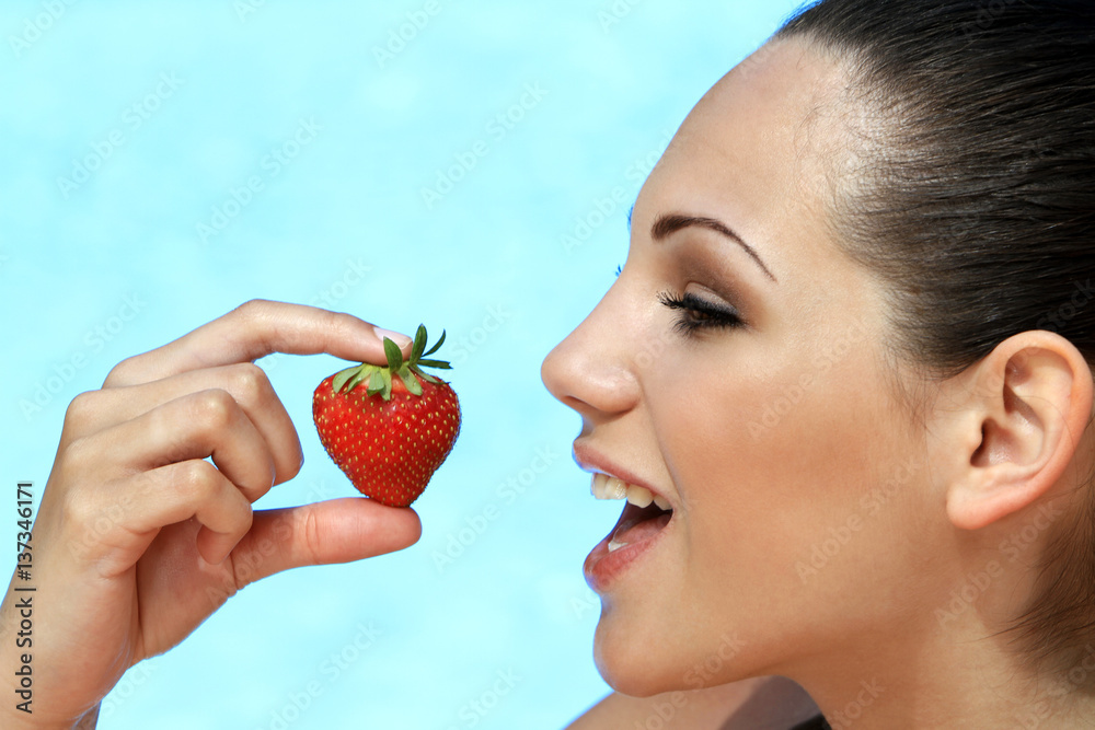 young woman eating strawberries at the pool on holiday young woman eating strawberries at the pool on holiday