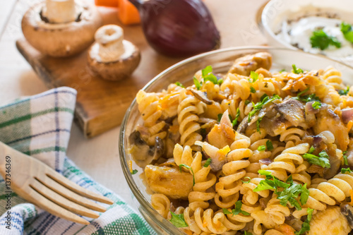 Integral pasta with chicken, mushrooms, vegetables, spices and Greek yogurt. White wooden background.