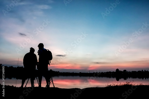 Silhouette photographers with sunset background