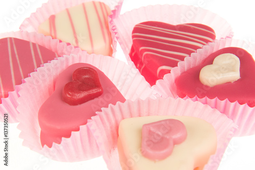 Close-up of a pink heart shaped petit fours cakes seen from the side on a white background photo