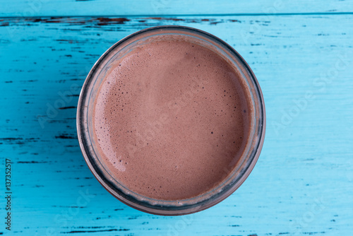 Top view of chocolate milkshake on blue wooden table