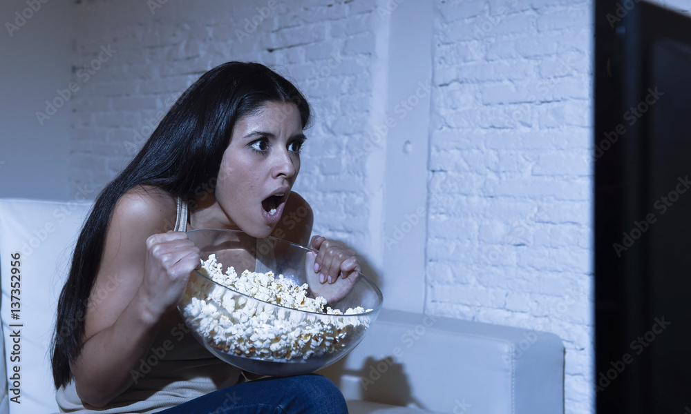 Naklejka premium woman at home sofa couch in living room watching television scary horror movie or suspense thriller