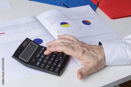 main homme senior calculant ses revenus d'obligations et action savec une calculette  photo