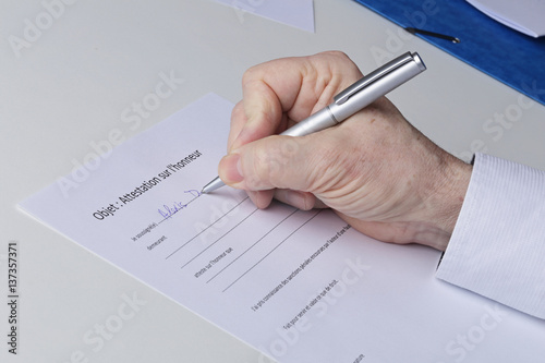 Konstfotografi main homme senior signant une attestation sur l'honneur