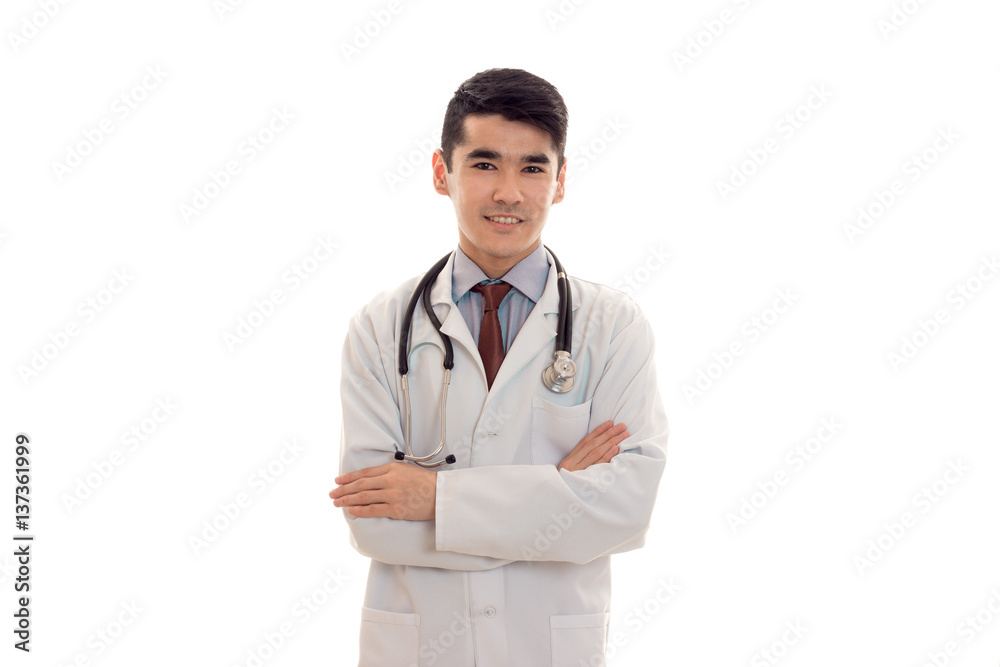 pretty young brunette man doctor in white uniform with stethoscope looking and smiling on camera isolated in studio pretty young brunette man doctor in white uniform with stethoscope looking and smiling on camera isolated in studio