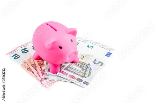 Tableau sur toile Piggybank standing on five and ten Euro banknotes