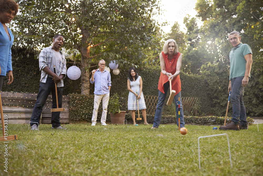Group Of Mature Friends Playing Croquet In Backyard Together Group Of Mature Friends Playing Croquet In Backyard Together