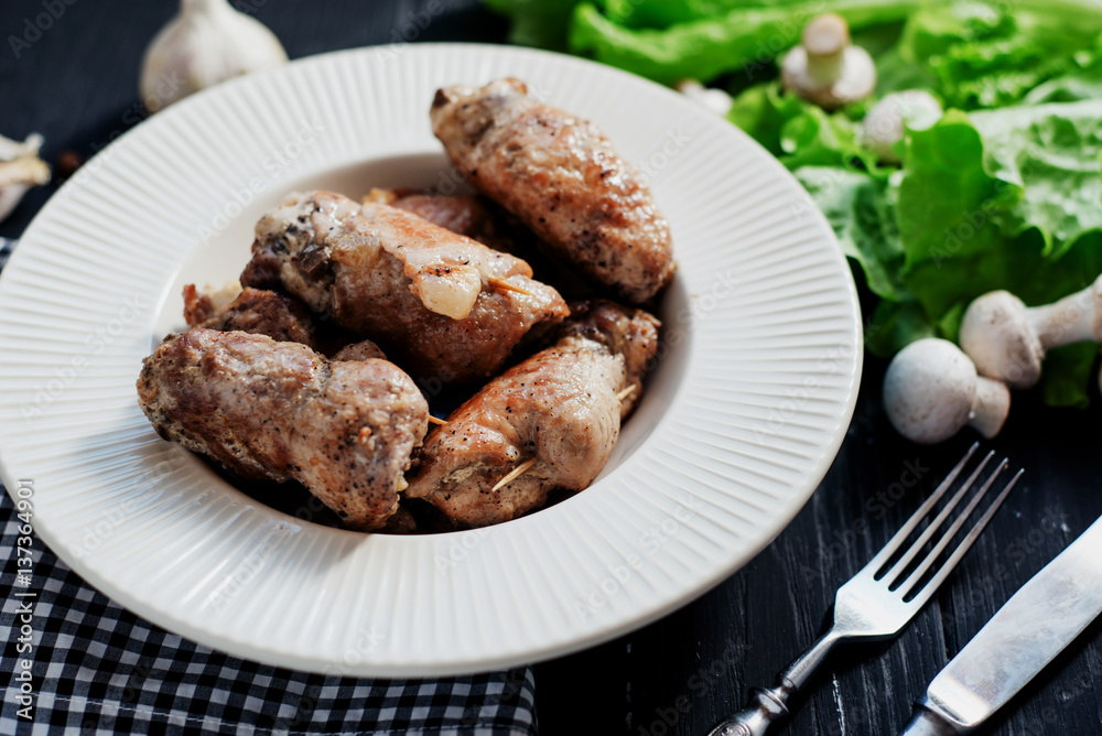charcuterie, meat, baked pork rolls with mushrooms, herbs and lettuce on a wooden black background charcuterie, meat, baked pork rolls with mushrooms, herbs and lettuce on a wooden black background