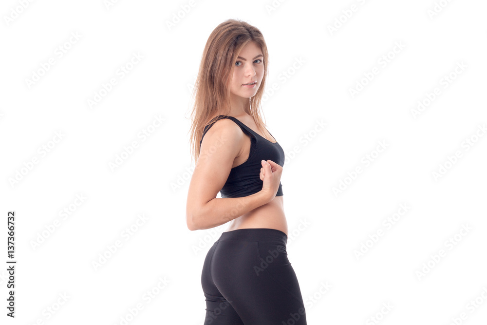 Fitness girl in black stands sideways isolated on white background Fitness girl in black stands sideways isolated on white background