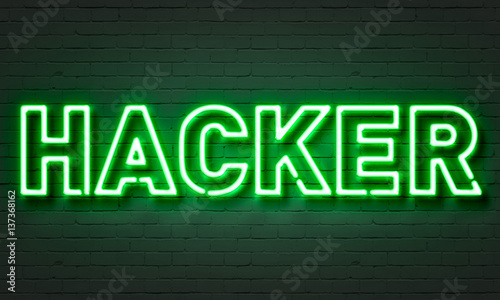 Hacker neon sign on brick wall background.