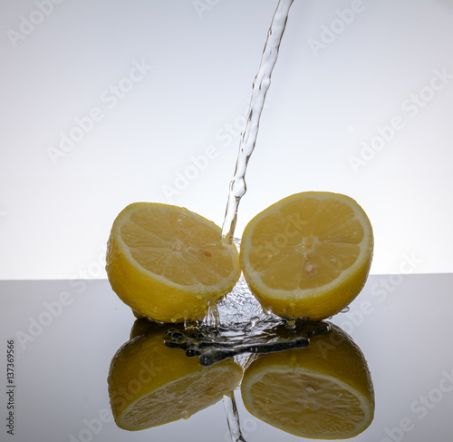 Zwei Zitrone - Limette geschnitten mit Spiegelung und Wasser vor weissem Hintergrund