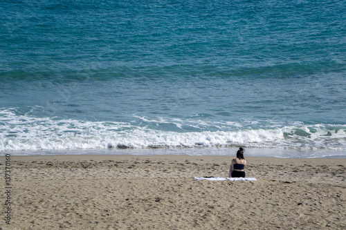 A woman sits on the beach enjoying a good book while relaxing