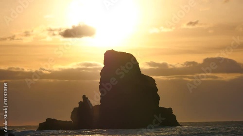 Stunning sunset in Talisker bay on west coast of the Isle of Skye in Scotland during an windy sunset. Sharp rocky tower above foamy sea of the Hebrides, waves crashing against to sharp rock 