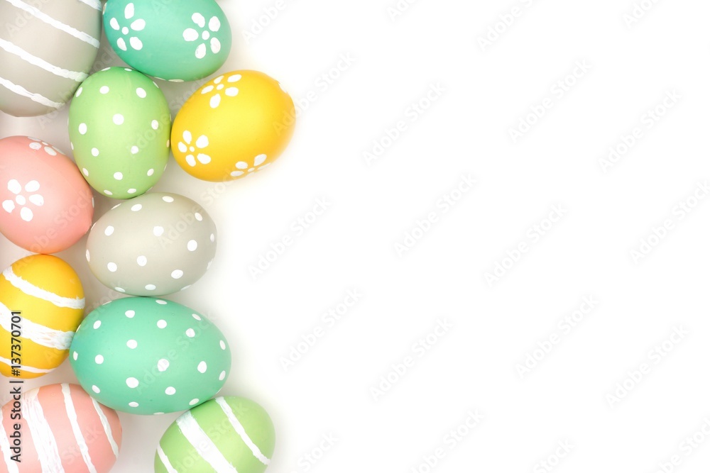 Side border of hand painted pastel Easter eggs over a white background