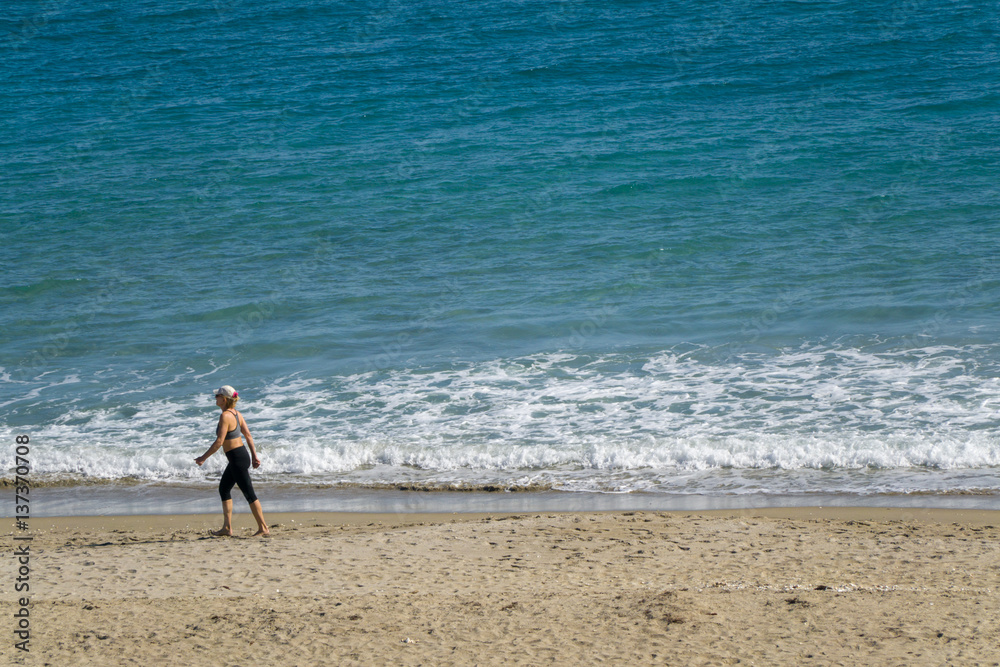 A woman gets her morning exercise walking on the beach A woman gets her morning exercise walking on the beach