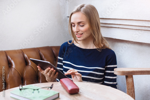 Cafe city lifestyle woman on tablet texting text message on tablet app sitting indoor in trendy urban cafe.