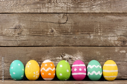 Row of hand painted Easter eggs over a rustic wooden background