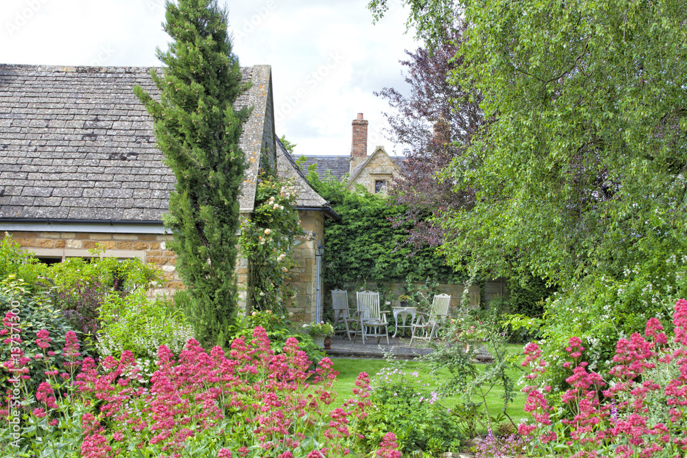 Φωτογραφία Enclosed patio with chairs and table in charming Cotswolds cottage garden full of flowers in bloom, mature trees