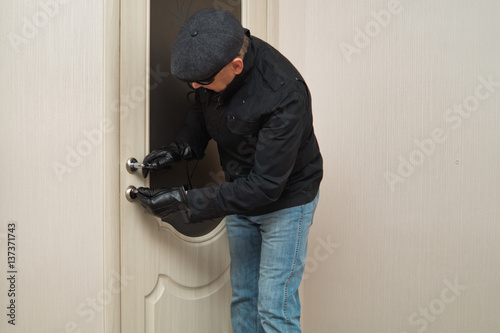 A man in a black jacket and dark glasses opens the door key