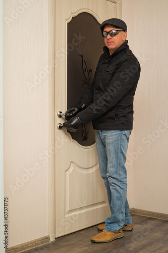 A man in a black jacket and dark glasses opens the door key