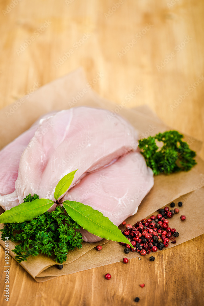 Raw chicken breasts and spices on wooden cutting board, close up view Raw chicken breasts and spices on wooden cutting board, close up view