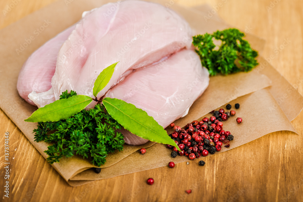 Raw chicken breasts and spices on wooden cutting board, close up view Raw chicken breasts and spices on wooden cutting board, close up view