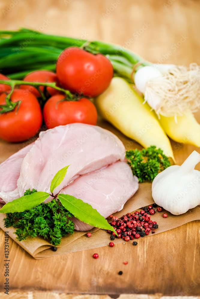 Raw chicken breasts and spices on wooden cutting board, close up view Raw chicken breasts and spices on wooden cutting board, close up view