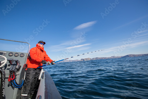 man with a fishing rod in his hands. Red Jacket. sports glasses. fisherman