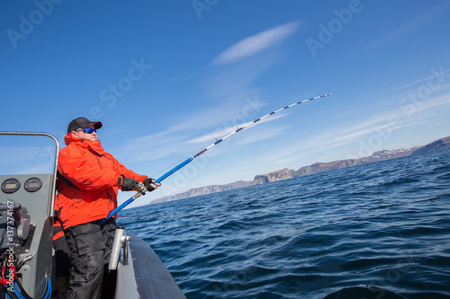 man pulls a fish out of water. Red Jacket. sports glasses. fisherman