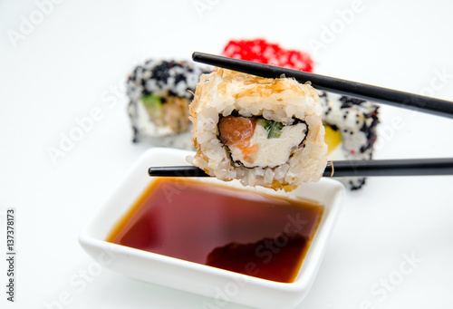 A piece of sushi held by chopsticks