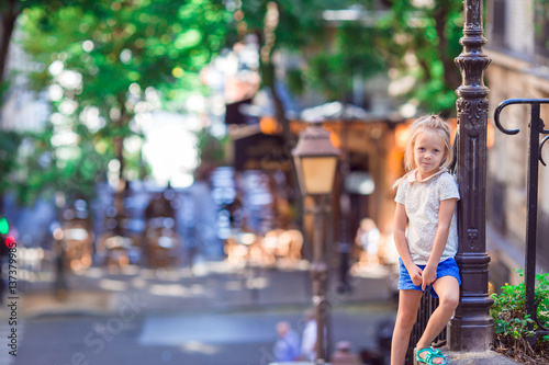 Adorable happy little girl outdoors in Montmartre. Portrait of caucasian kid enjoy summer vacation in Europe