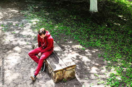 a lonely young man sitting in the park waiting for the girl. view from above