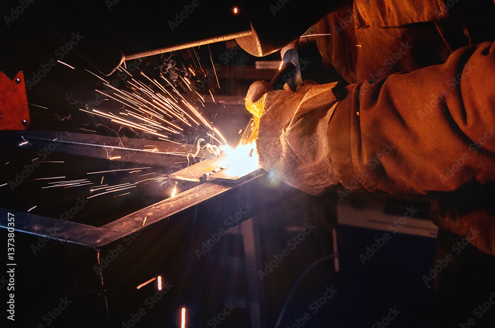 Welder in a protective mask in a dark shop floor prepared to work on metal Welder in a protective mask in a dark shop floor prepared to work on metal