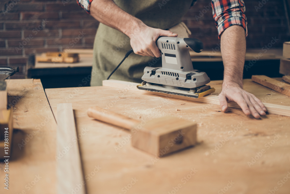 closeup photo of cabinetmaker grinds wooden plank on tabletop at workstation closeup photo of cabinetmaker grinds wooden plank on tabletop at workstation
