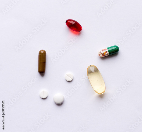 Tabs Vitamins, omega 3, Medications tablets and capsules in a beaker. Medications tablets, suppository bottles, capsules and thermometer on wooden table photo