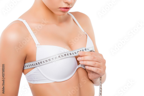 Close up of young woman measuring her bust size with tape measure photo