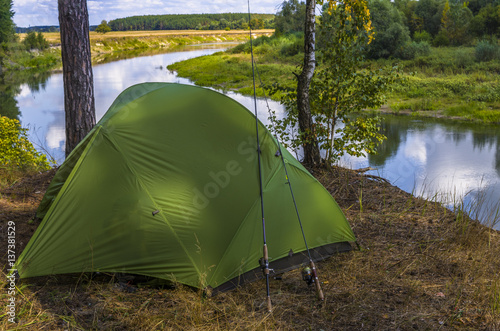 Fishing camping tent on the river shore. Travel, leisure and tourism in nature.