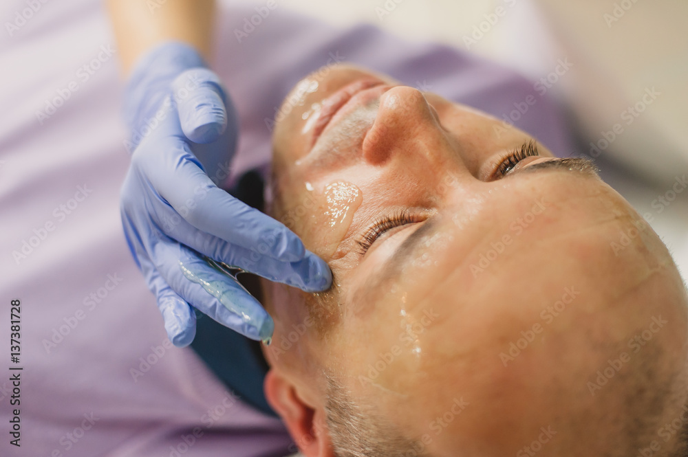 Relaxed man having a face massage and a peeling treatment Relaxed man having a face massage and a peeling treatment