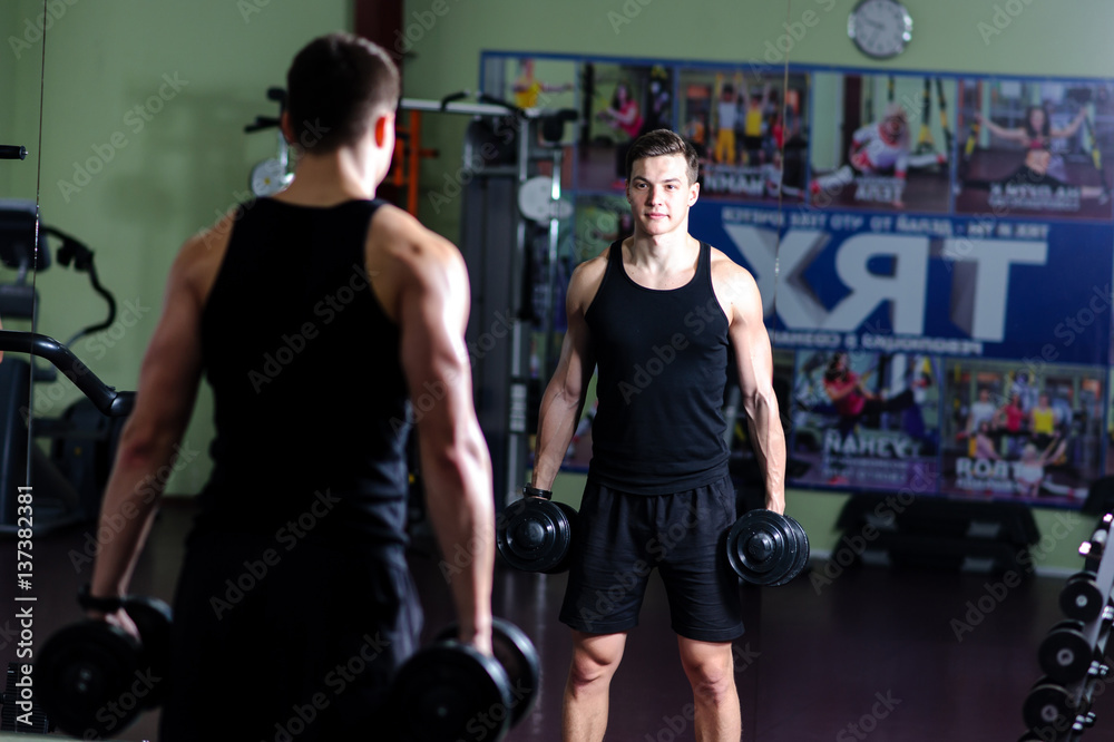 handsome guy is engaged with a dumbbell in the gym handsome guy is engaged with a dumbbell in the gym