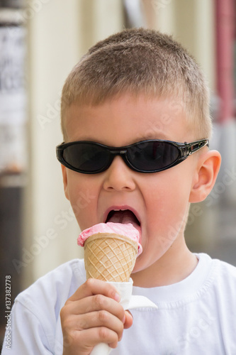 Boy in sunglasses eating ice cream outdoors