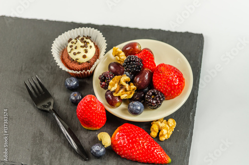 top view on set of various nuts and fruit with chocolate muffin with a white cream