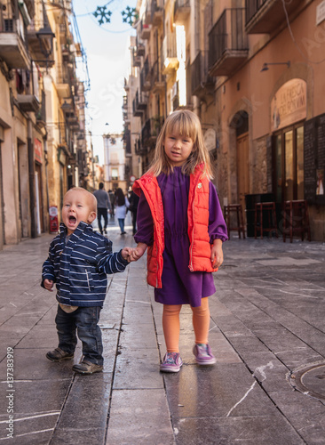 Brother and sister are walking by the street in Tarragona, Spain