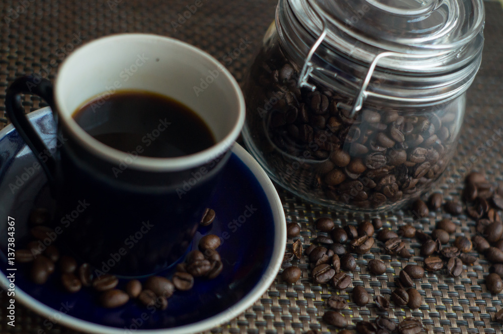 black coffee and a jar of coffee beans stand on the table black coffee and a jar of coffee beans stand on the table