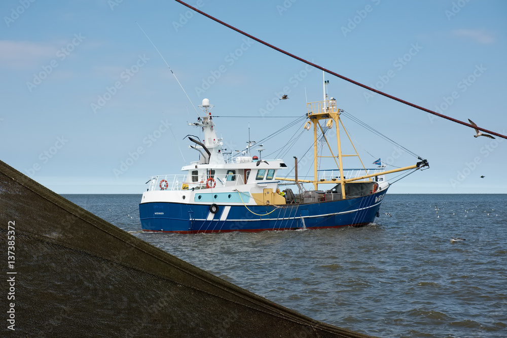 Fishing boat framed by fishing net in the Waddenzee, the Netherlands.