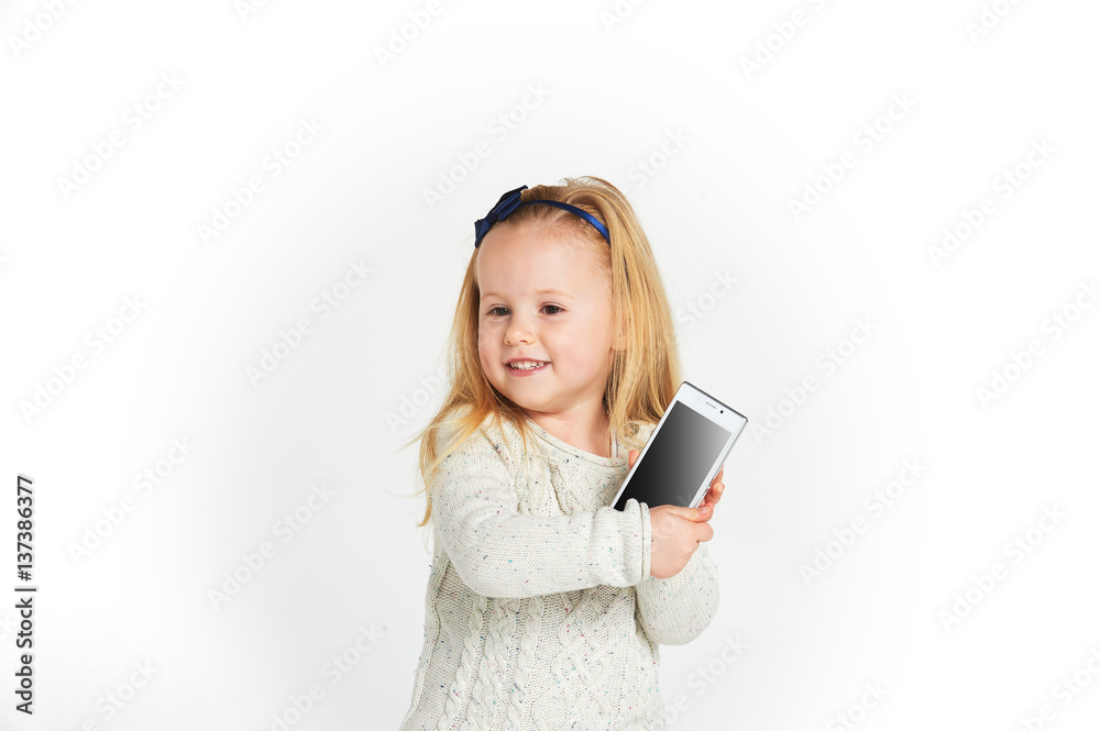 Cute little girl smiling and uses a smartphone, phone. Cute little girl smiling and uses a smartphone, phone.