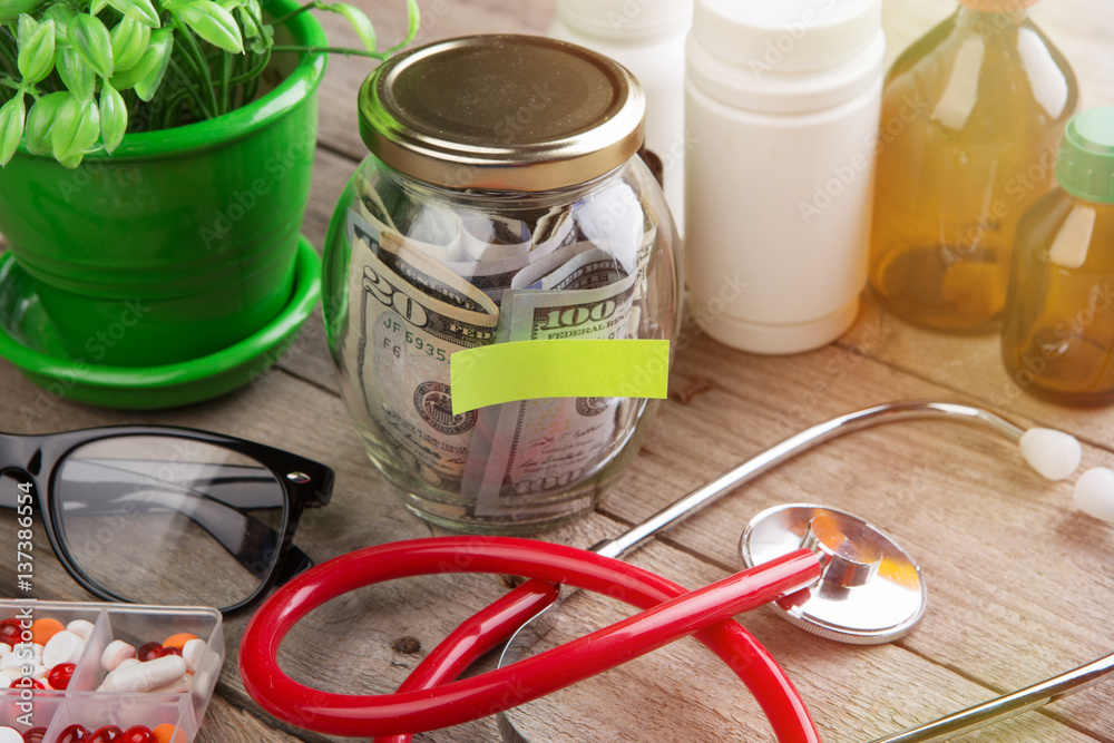 Saving money for health care insurance - money glass, stethoscope, pills and bottles Saving money for health care insurance - money glass, stethoscope, pills and bottles