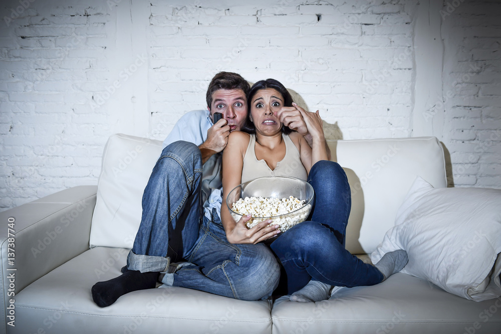 Naklejka premium attractive couple having fun at home enjoying watching television horror movie show