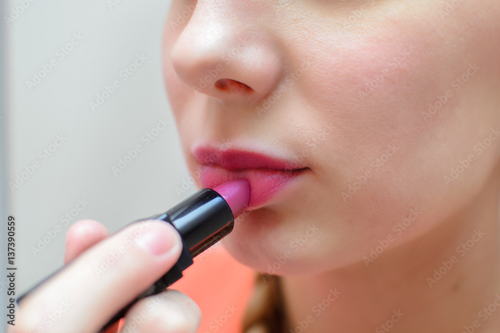Girl paints her lips purple lipstick