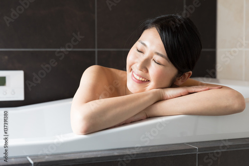 attractive asian woman relaxing in bathtub