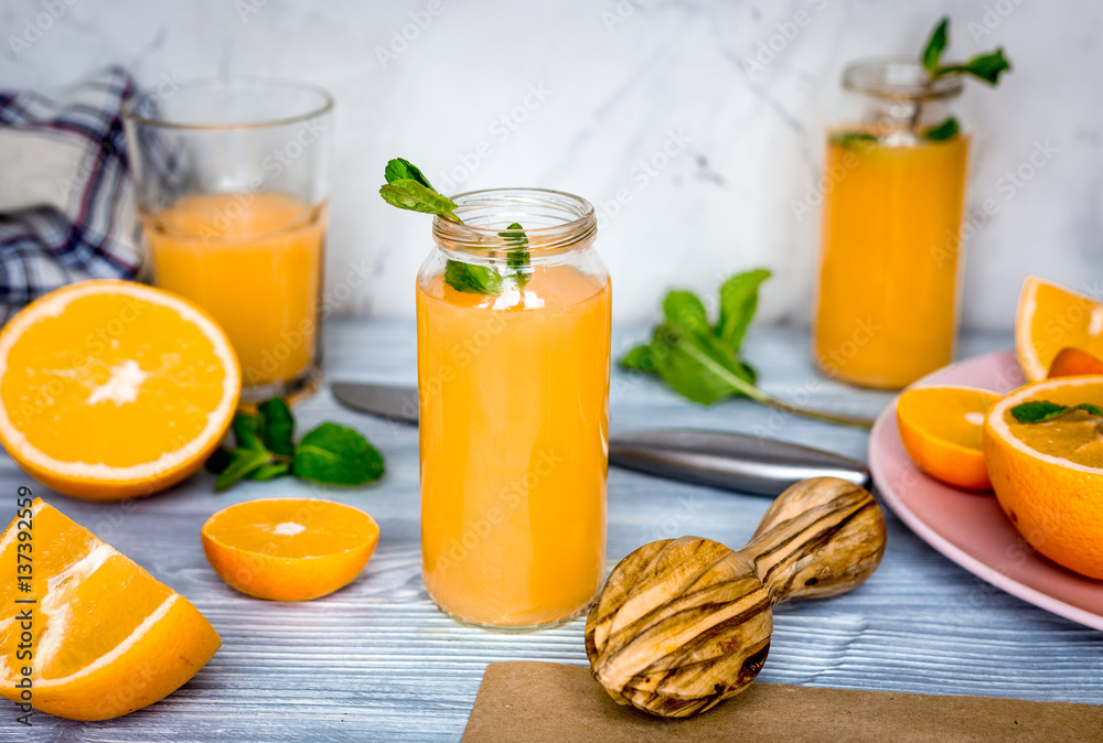 healthy orange cocktail with mint leaves in bottle on kitchen background